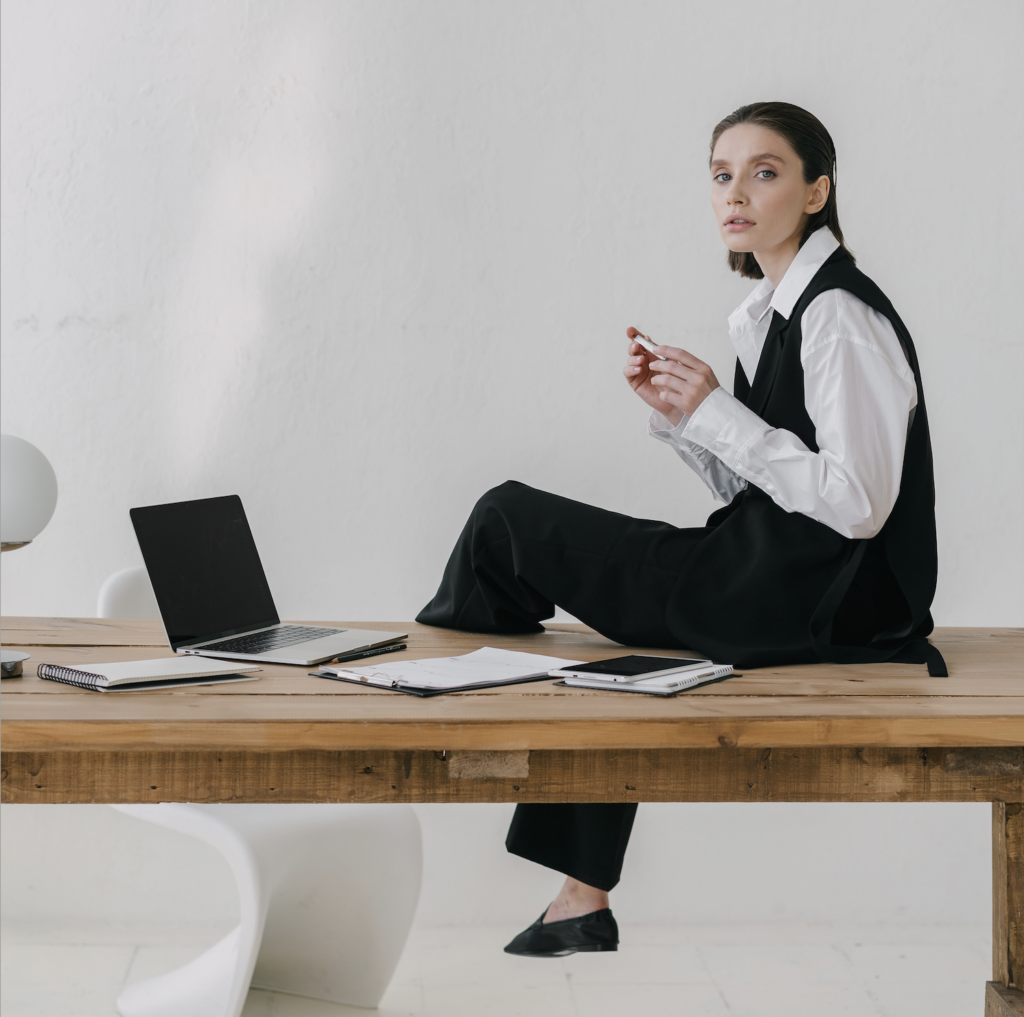 Photo by Mikhail Nilov: https://www.pexels.com/photo/woman-sitting-on-wooden-table-7677862/